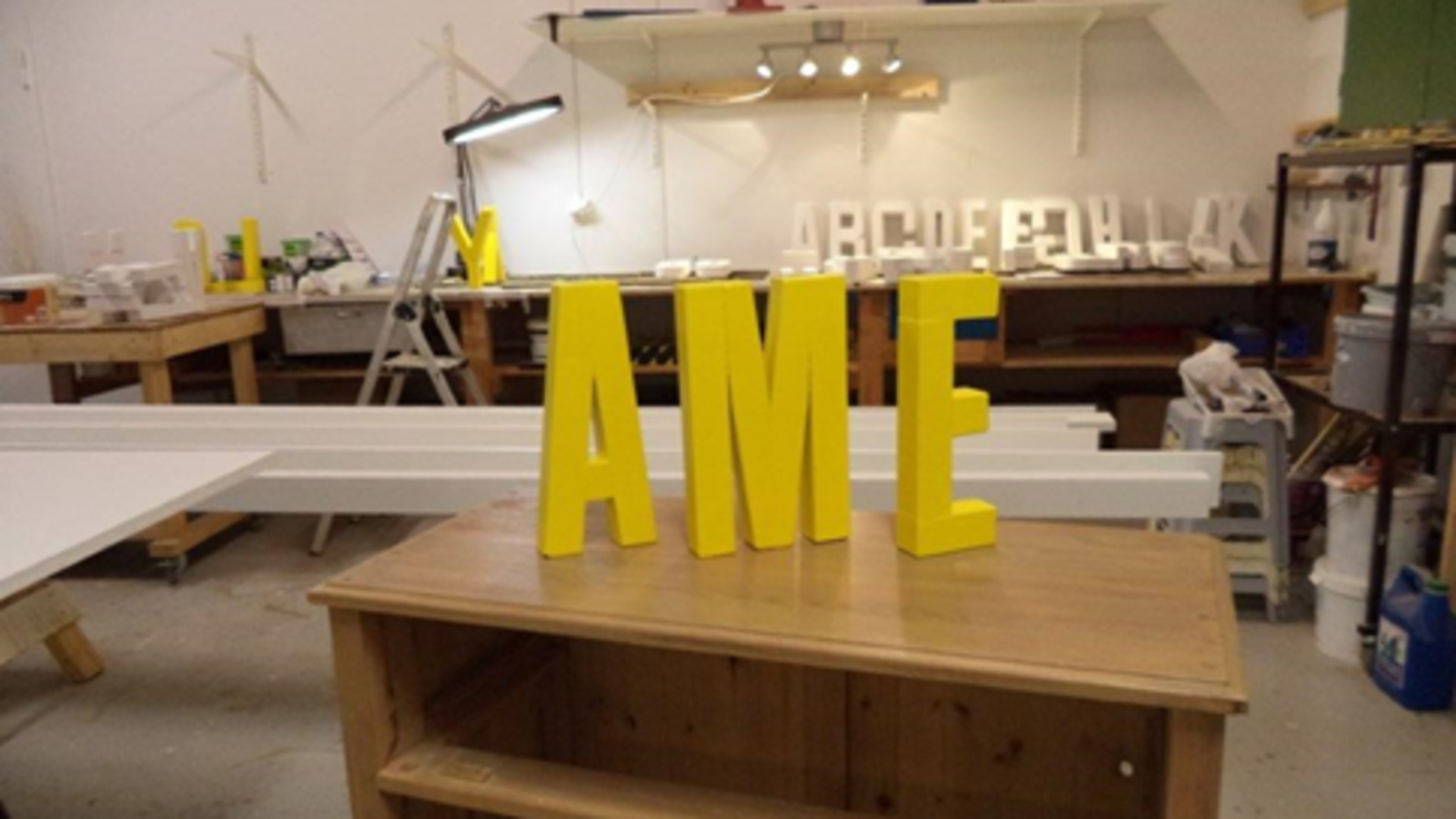 Tre gula bokstäver som formar ordet "AME".