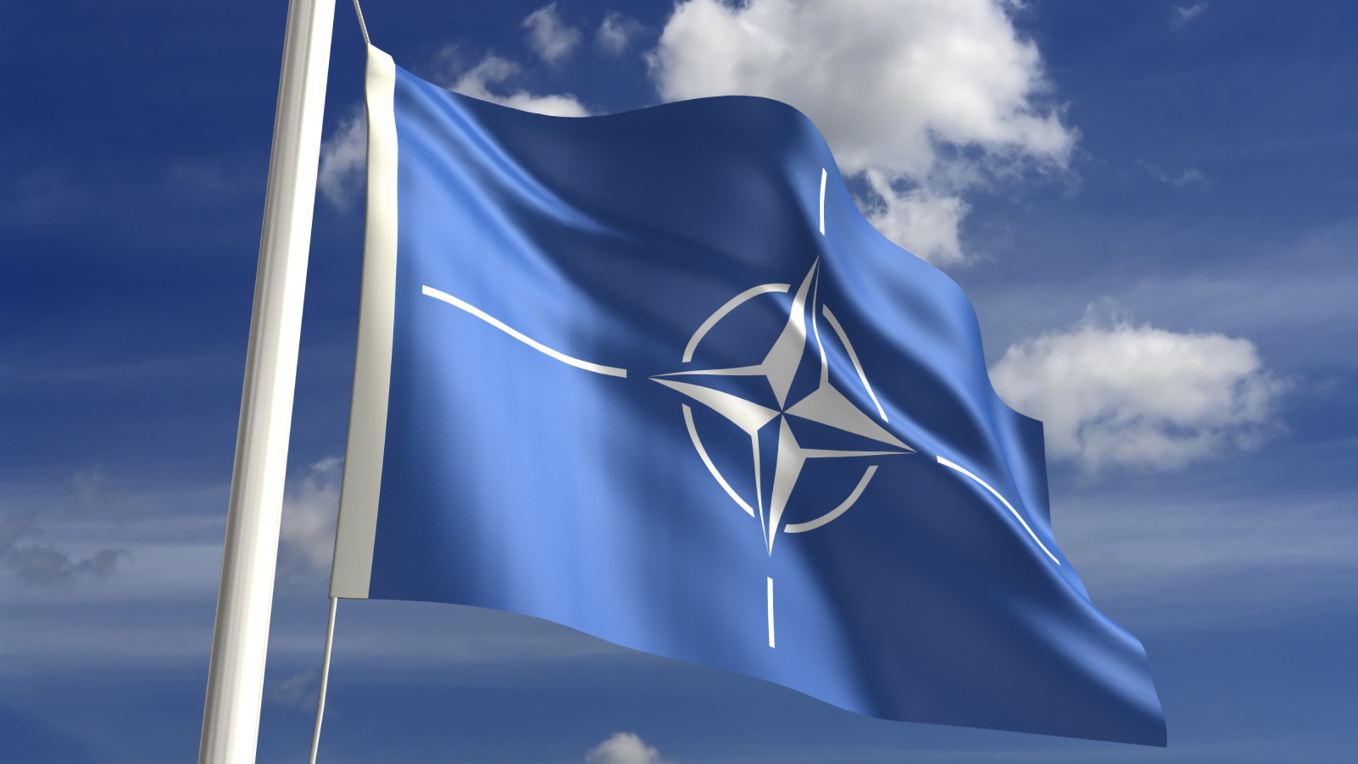 Natoflaggan vajar mot en blå himmel.