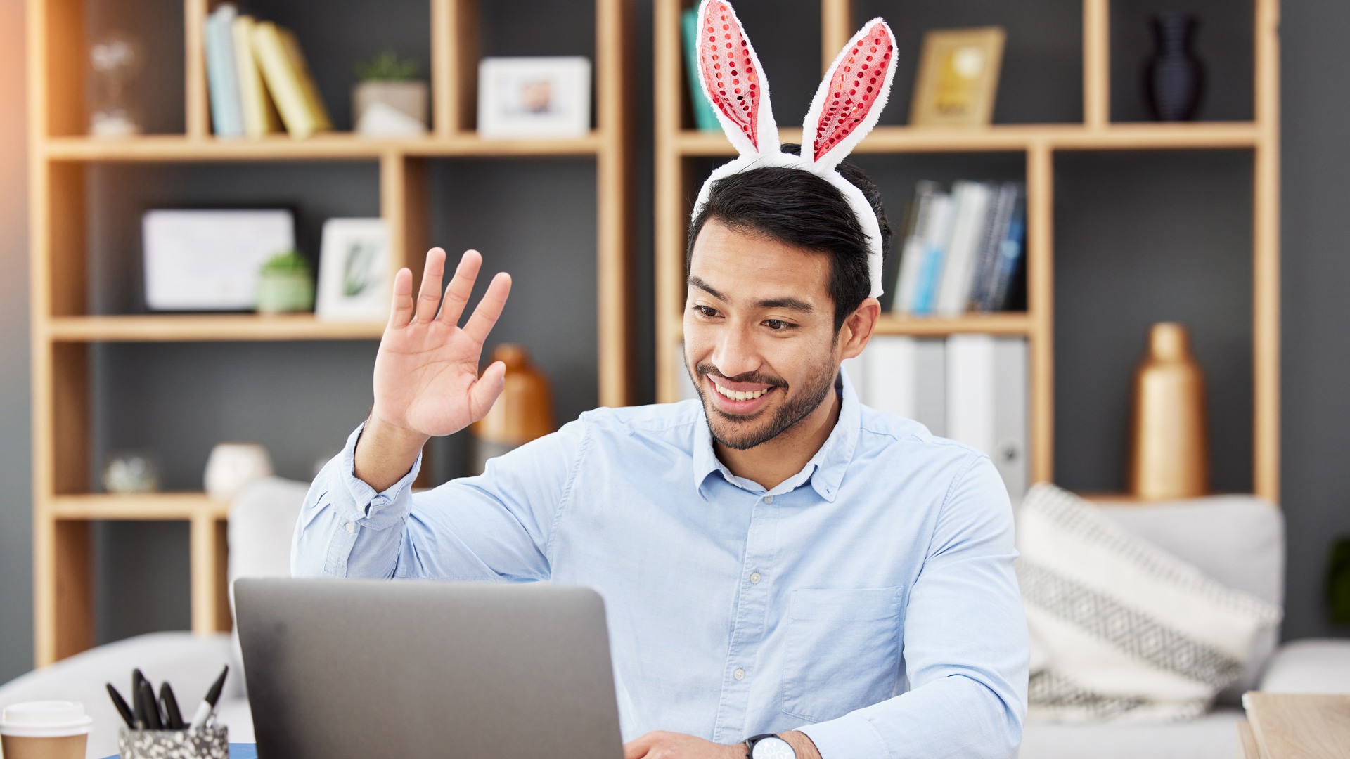 Easter bunny, ears and man on online meeting at home with computer screen and greeting. Remote work, holiday and rabbit costume in virtual call in house for digital education class with male teacher.
