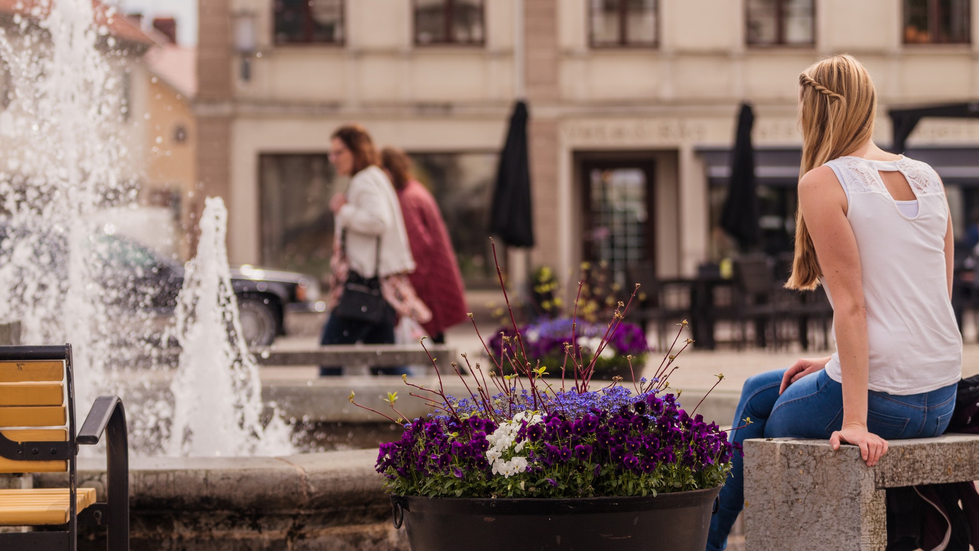 En person sitter vid fontänen på torget i Hjo.