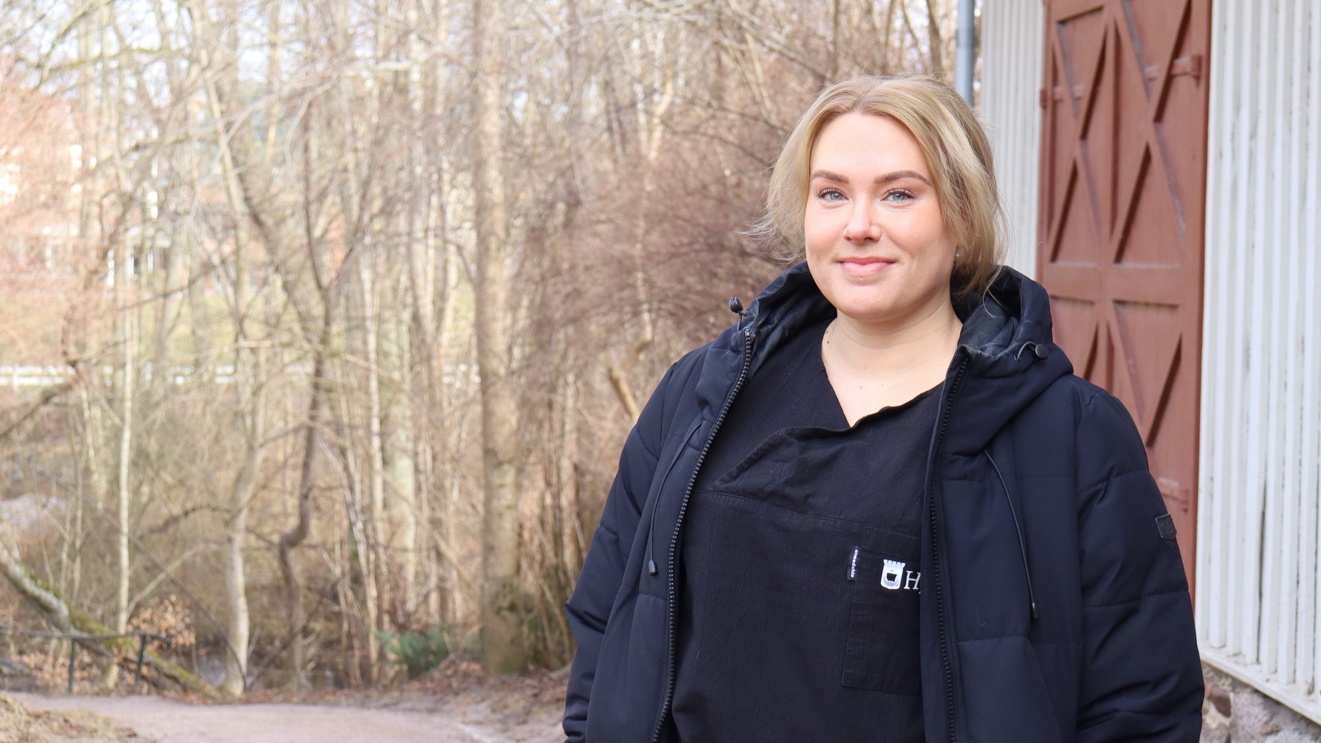 Emma Kallio, undersköterska i hemvården framför ett trähus.