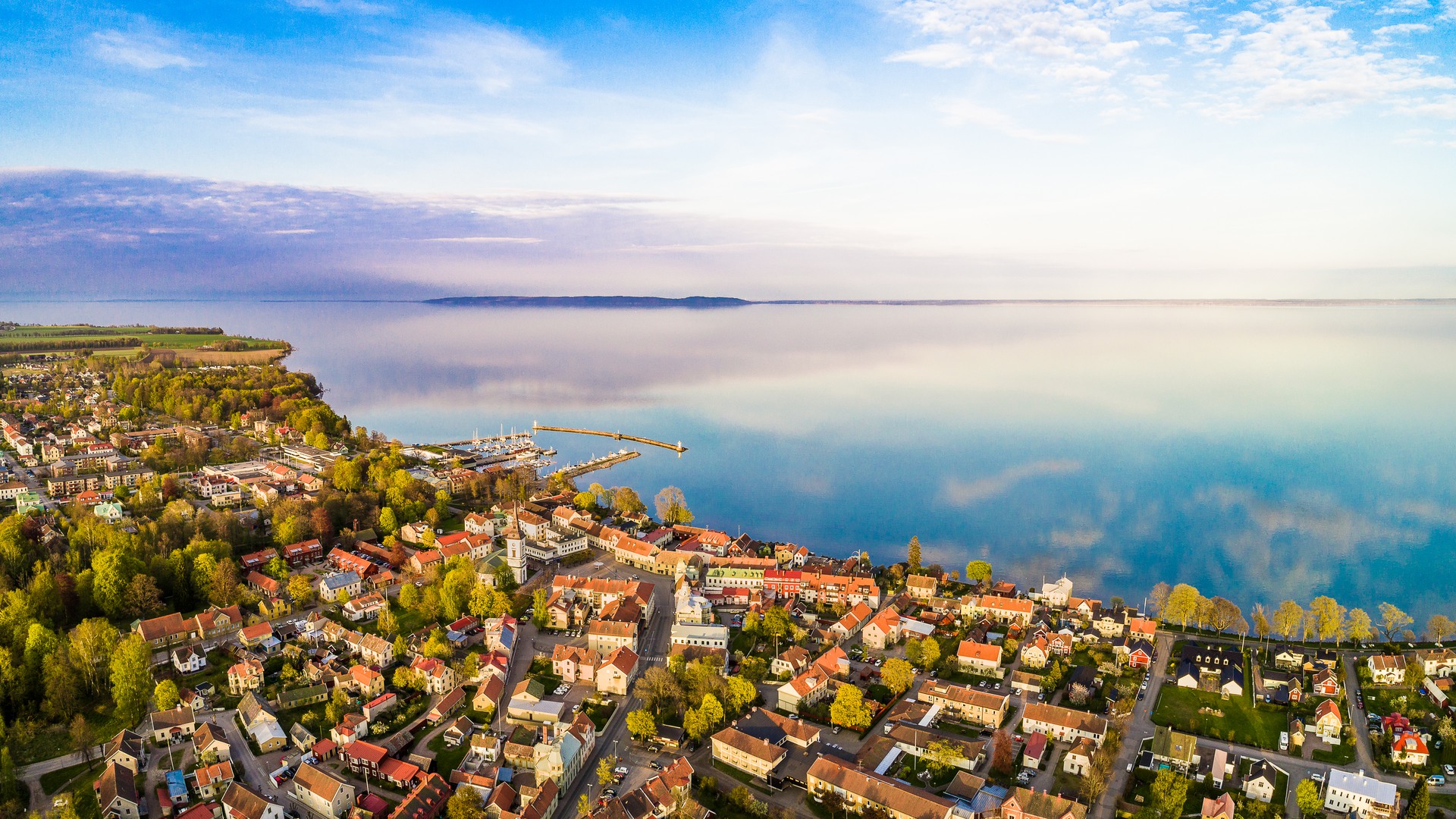 Flygbild med vy över Hjo stad, hamnen och Vättern.