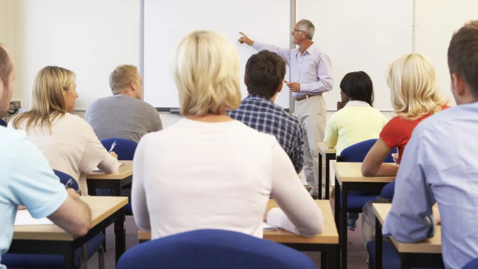 Vuxna elever sitter i klassrummet och lyssnar på läraren.