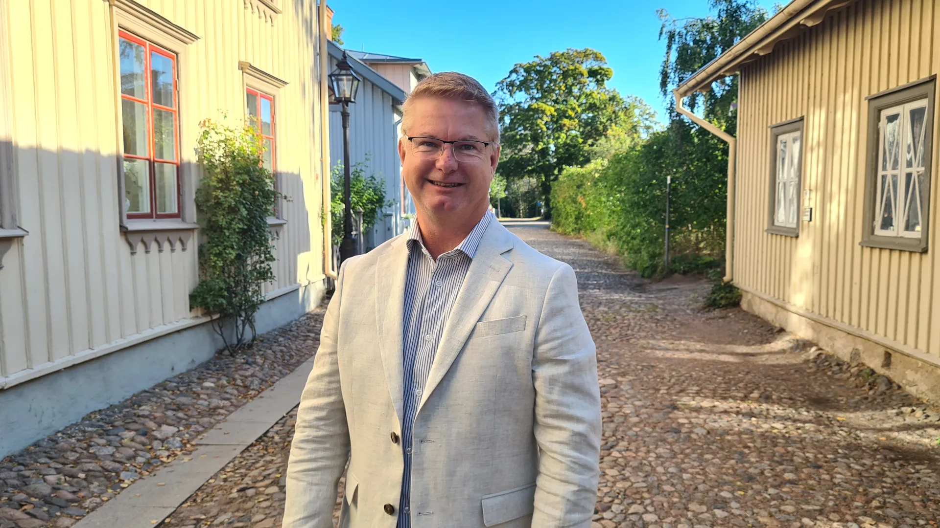 Ekonomichef Sören Andersson på en kullerstensgata med träfasader.