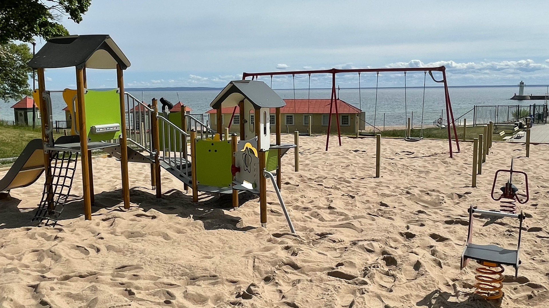 Lekplats med klätterställning och gungor på sand vid Guldkroksbadet i Hjo