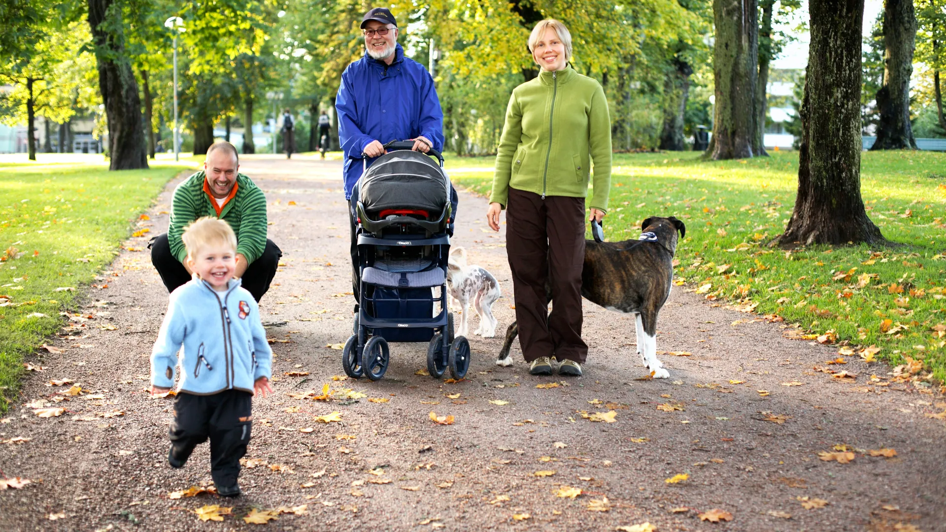 En familj med hund på promenad i en park.