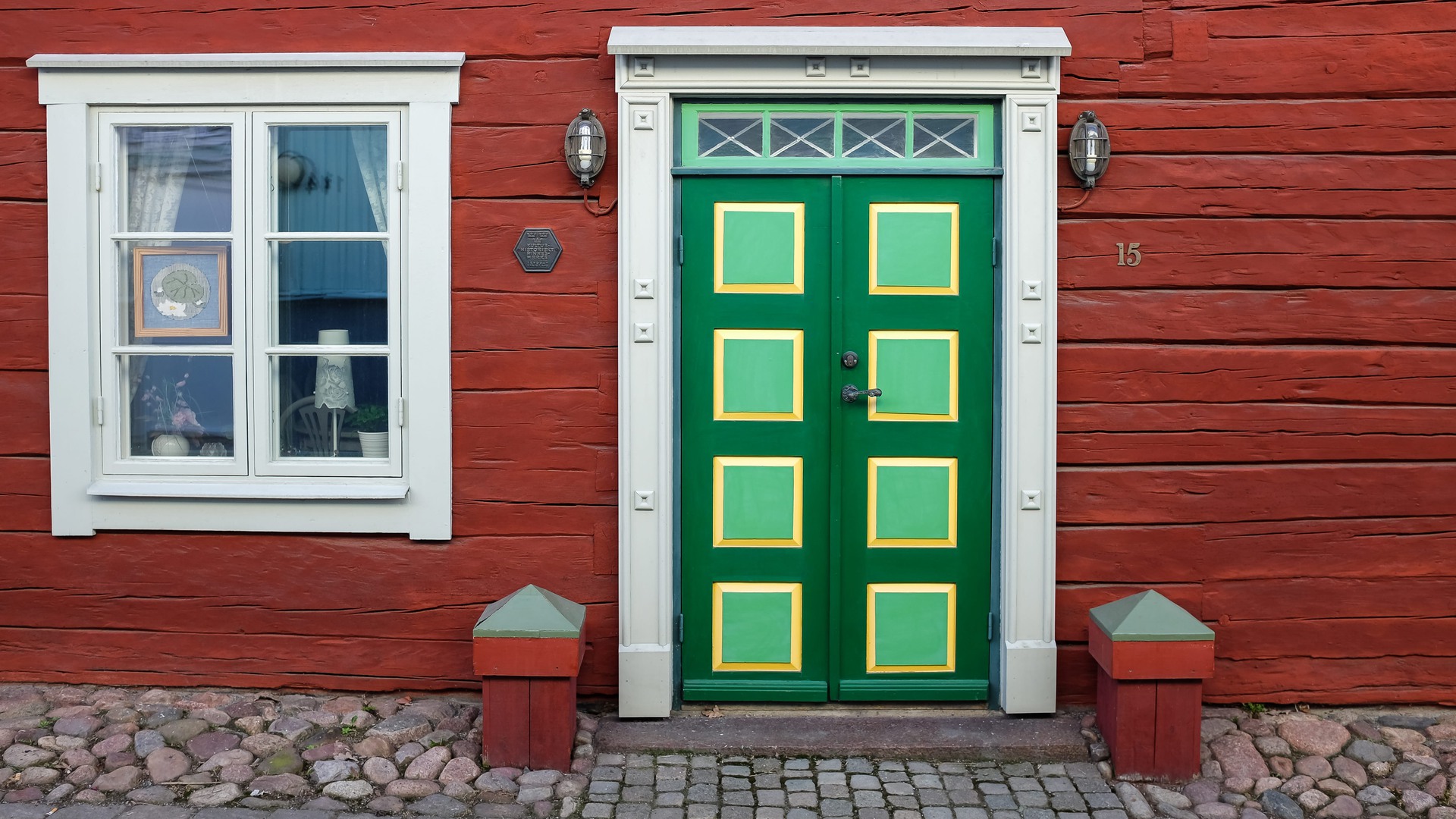Ett rött hus med gammal dörr i grönt och gult.