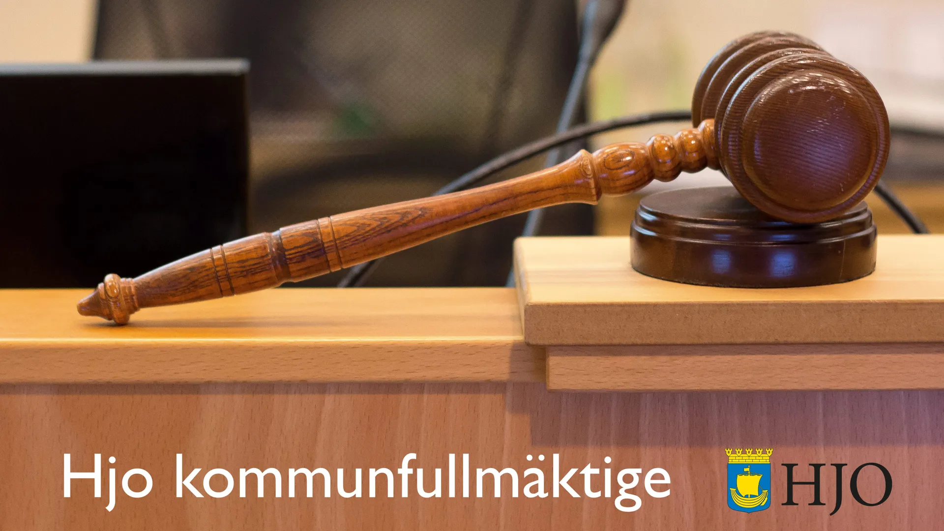 En beslutsklubba på ett bord, samt texten "Hjo kommunfullmäktige".