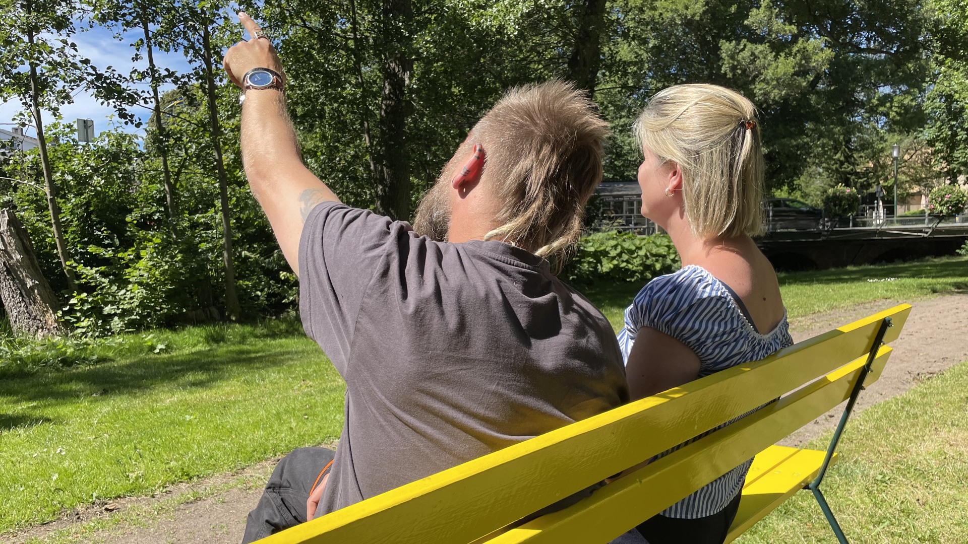 Två personer sitter på en gul bänk och pratar.