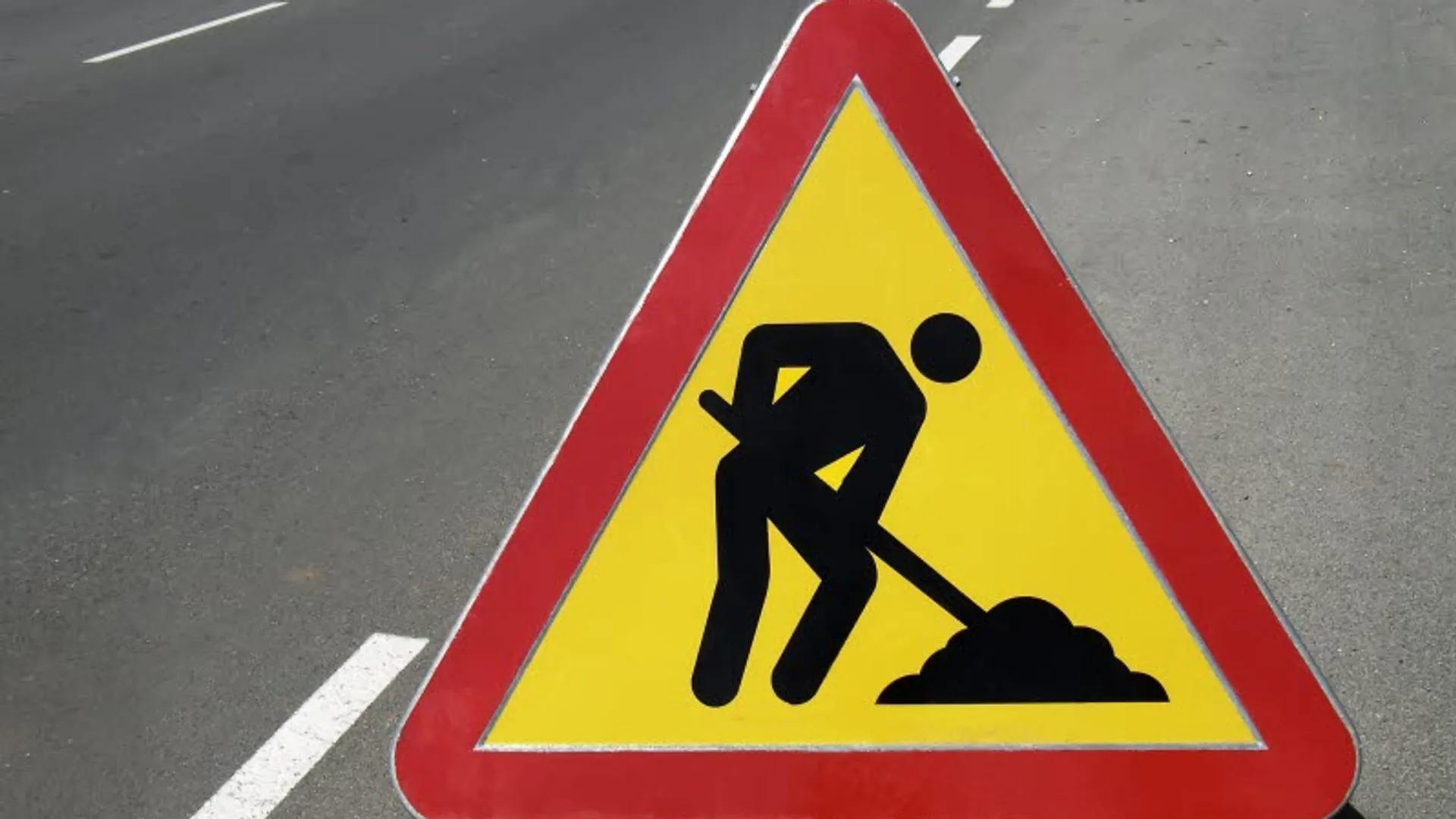 Varningsskylt för vägarbete på asfaltsväg.