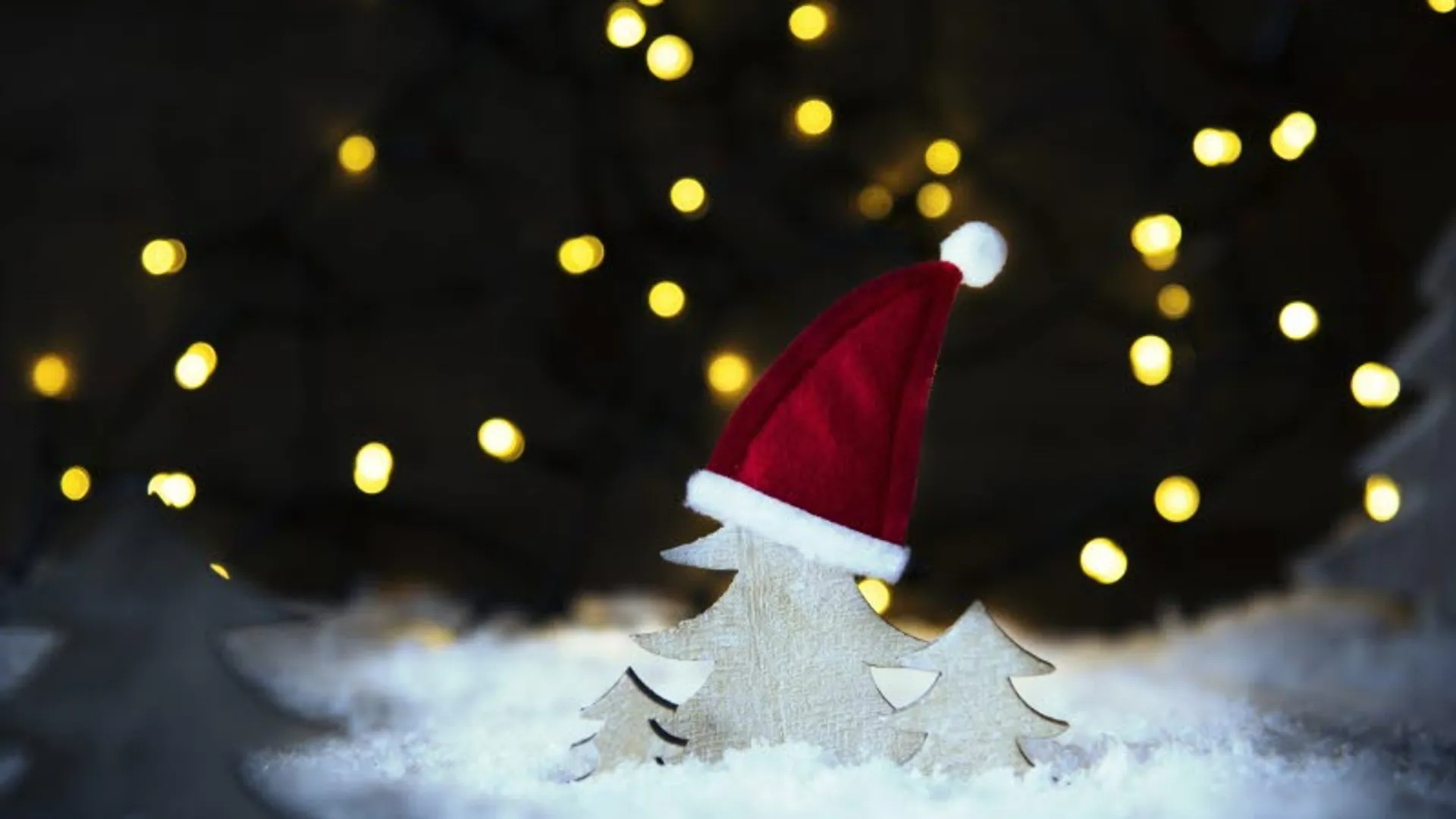 Ett juligt landskap med bomullssnö, granar i papp, en tomteluva på grantoppen och stjärnor i bakgrunden.