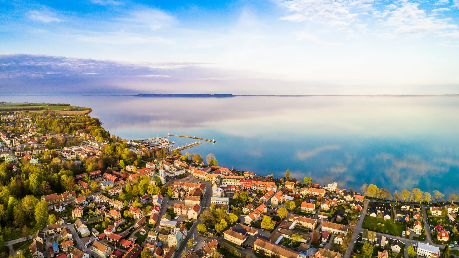 Flygbild med vy över Hjo stad, hamnen och Vättern.