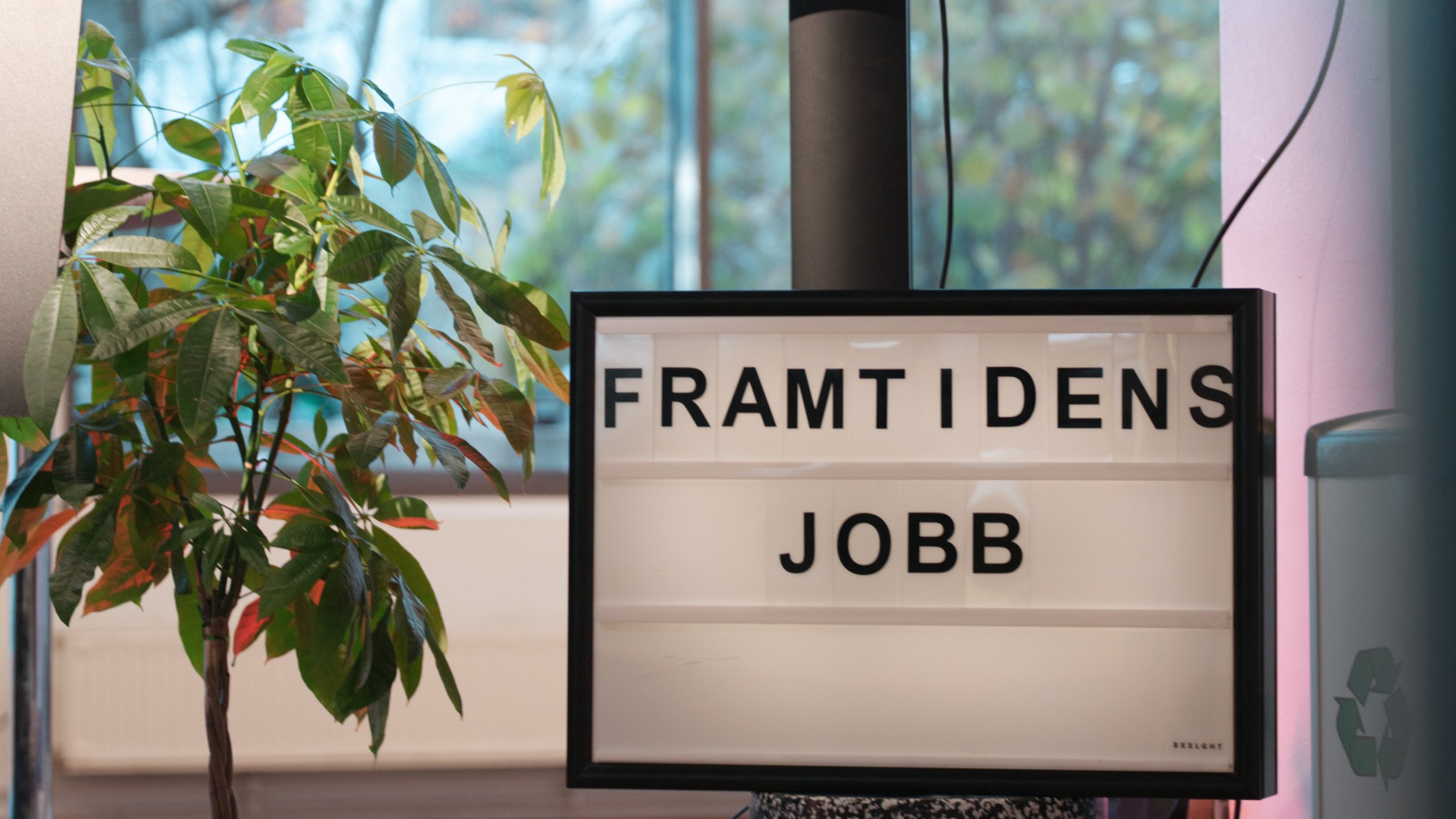 En skylt som sitter på en stolpe framför ett fönster
