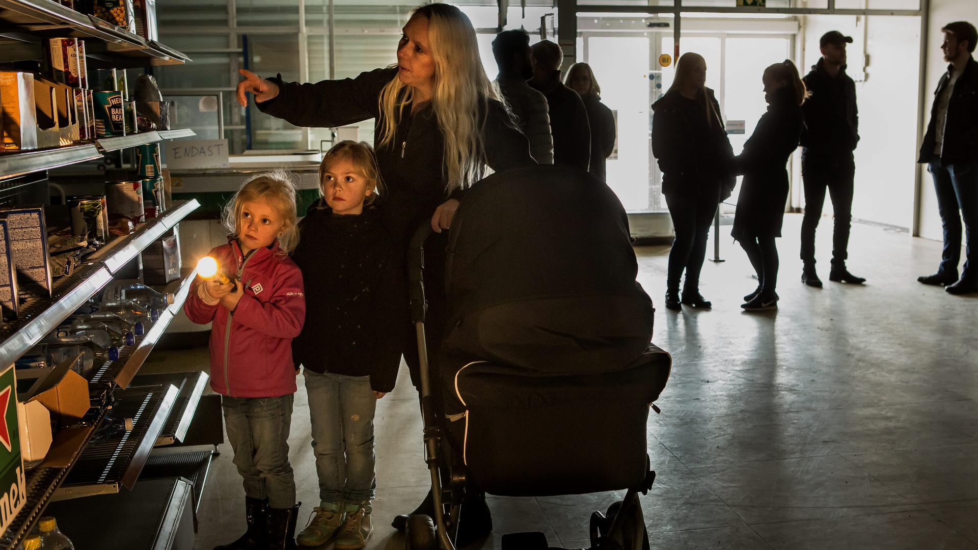 En familj står vid en butikshylla i en mörk butik.