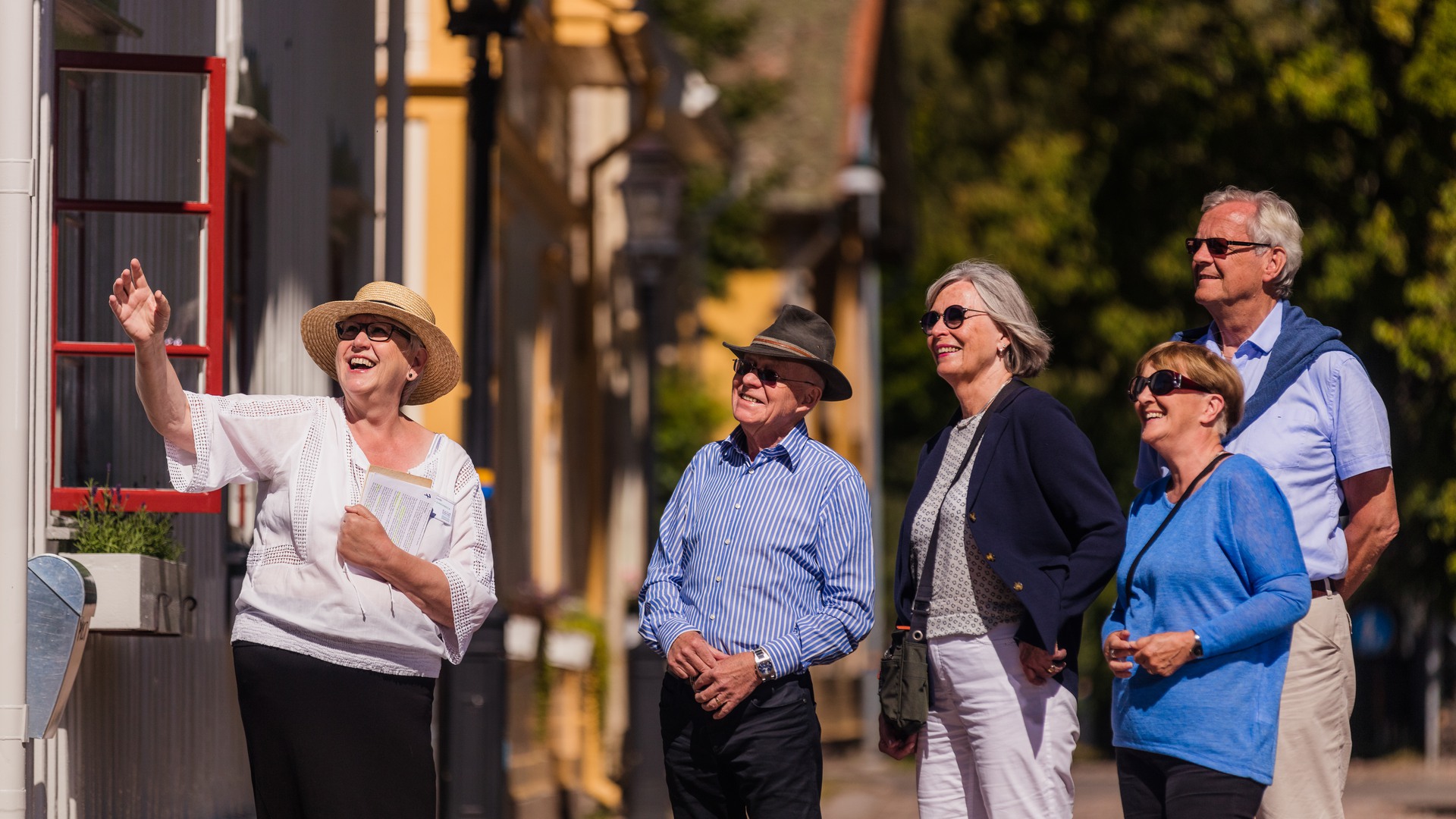 En guide visar fyra turister en av villorna i stadsparken.