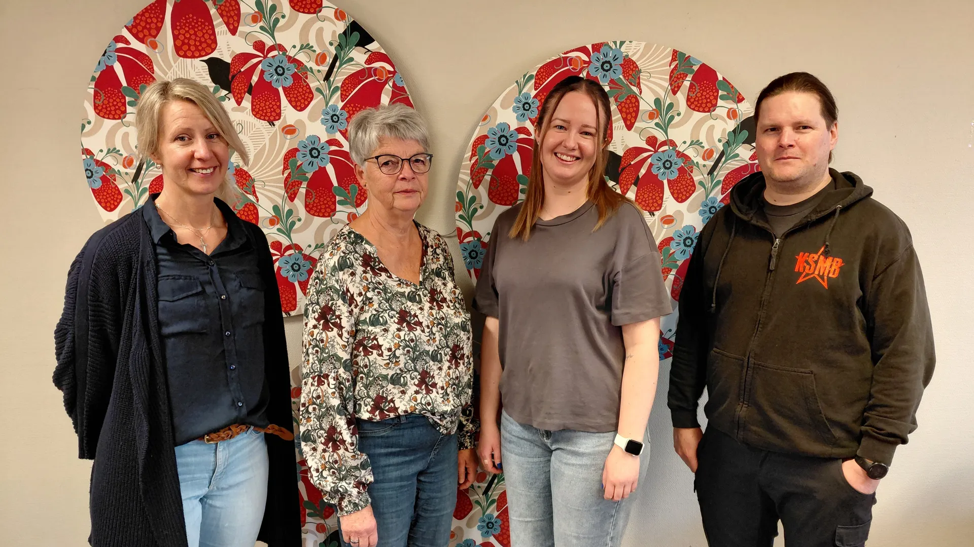 Fyra personer framför en vägg med färgglatt mönster.