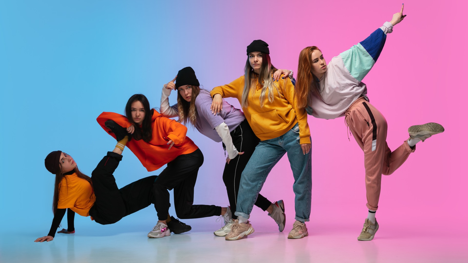Group of dancers, boys and girls dancing hip-hop in stylish clothes on colorful gradient background at dance hall in neon. 